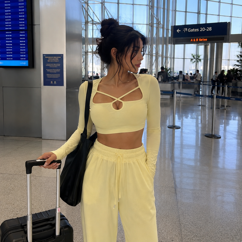 Woman wearing butter yellow long sleeve crop top and relaxed lounge pants at airport with casual chic travel outfit style