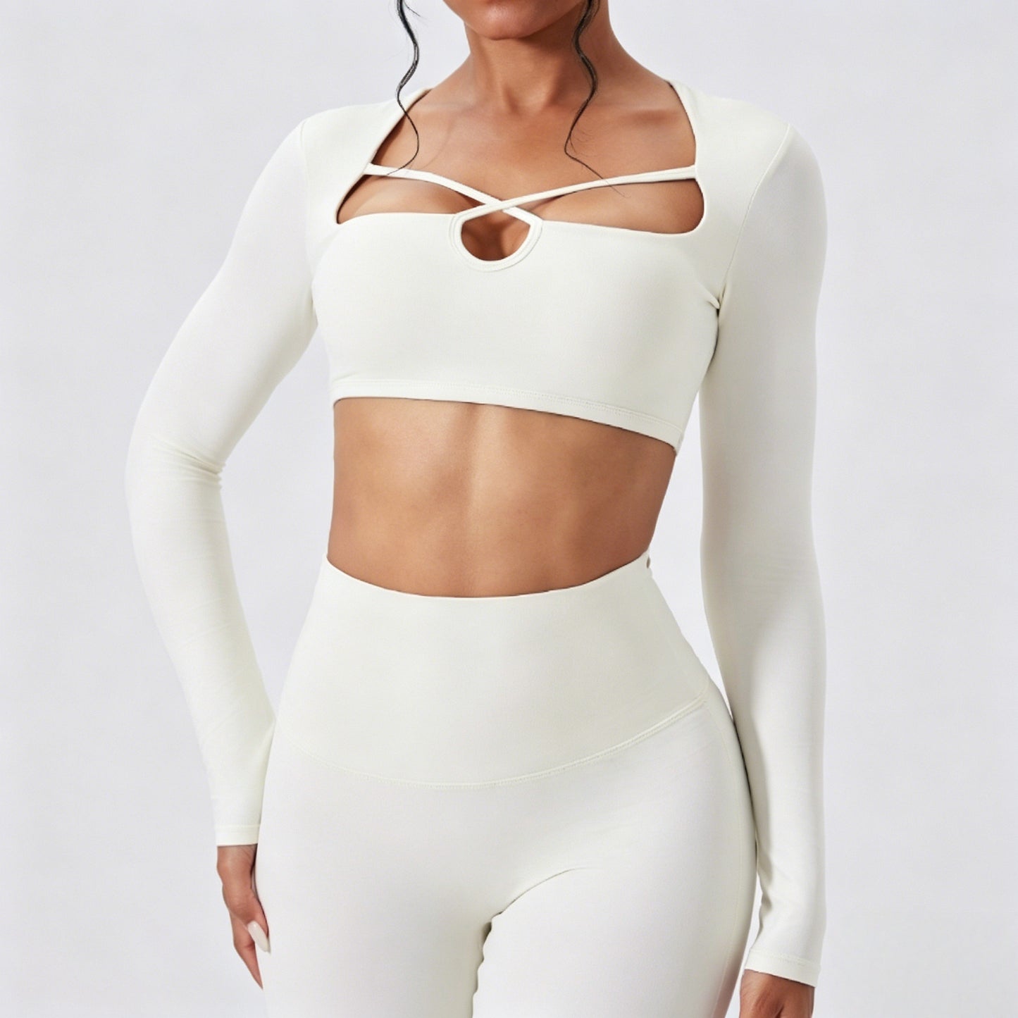 Model wearing a sculpting ivory white long sleeve cutout crop top and high waist leggings set for workout and lounge wear